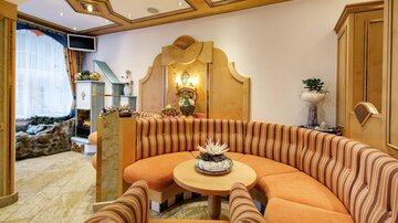 Ein einladender Lounge-Bereich mit orange-gestreiften Polstermöbeln und einem runden Tisch. Der Raum ist hell und freundlich, ideal zum Entspannen.