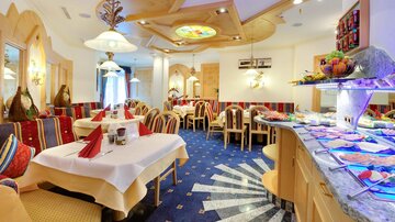 Ein gemütliches Restaurant mit eleganten Tischen und Stühlen. Der Buffetbereich ist reich dekoriert und bietet eine Vielzahl von Speisen.