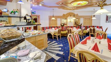 Ein gemütliches Restaurant mit Holzdekor und einer einladenden Atmosphäre. Die Tische sind festlich gedeckt und ein Buffetbereich ist sichtbar.