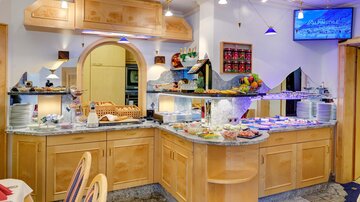 Ein großer Buffetbereich mit verschiedenen Speisen und frischem Obst. Die Einrichtung ist hell und einladend, ideal für ein Frühstück oder eine Mahlzeit.