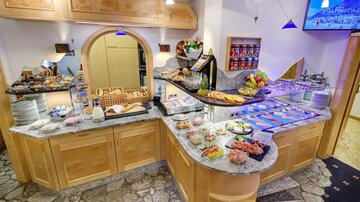 Ein ansprechend gedeckter Buffet-Tisch mit verschiedenen Speisen und frischem Obst. Die Holz- und Marmoroberflächen verleihen dem Raum eine einladende Atmosphäre.