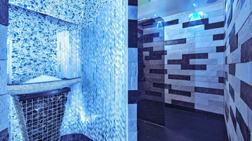 Ein moderner Wellnessbereich mit blauen Lichtern und glitzernden Fliesen. Der Raum ist elegant gestaltet und strahlt eine entspannende Atmosphäre aus.