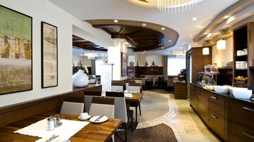 Ein modernes Restaurant mit eleganten Holzmöbeln und einem gemütlichen Ambiente. Die Einrichtung ist stilvoll und einladend, ideal für Mahlzeiten und Gespräche.