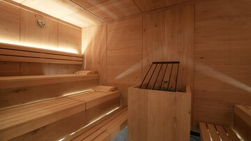 Eine moderne Sauna mit Holzbänken und sanfter Beleuchtung. Der Raum ist minimalistisch und einladend gestaltet.