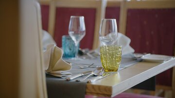 An elegantly set table in a restaurant. There are glasses, cutlery, and decorative napkins.