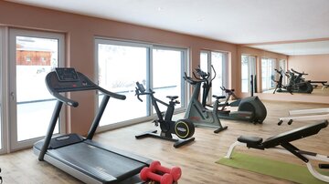 A modern gym with various training equipment.  
Large windows provide plenty of natural light and a pleasant atmosphere.