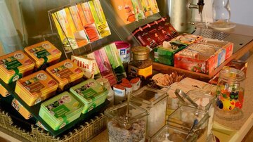 A table with various types of tea, cookies, and small containers with sugar and spices. The arrangement looks inviting and cozy.