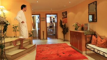 A stylish spa with warm colors and comfortable furnishings. A person in a bathrobe stands on the stairs, enjoying the relaxing atmosphere.