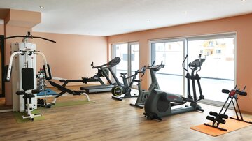 A modern gym with various training equipment. The room has large windows that let in a lot of light.