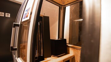 A modern, comfortable cabin with a wooden bench and equipment inside. Large windows allow for an outside view.