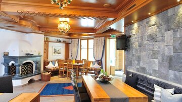 Ein gemütlicher Wohnraum mit Holzdekor und einer stilvollen Steinwand. Der Raum hat einen großen Tisch und eine angenehme Atmosphäre.