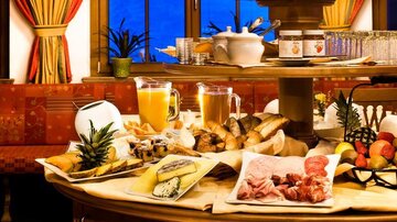 Ein schön gedeckter Tisch mit einer Vielzahl von Speisen und Getränken. Es gibt Brot, Aufschnitt, Obst und Säfte.