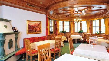 Ein gemütliches Restaurant mit Holzmöbeln und großen Fenstern. Die Tische sind elegant eingedeckt und die Wände sind mit Kunstwerken dekoriert.