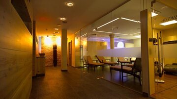 Ein moderner Fitnessbereich mit eleganter Beleuchtung und gemütlichen Sitzgelegenheiten. Die Holz- und Steinoberflächen verleihen dem Raum eine warme Atmosphäre.