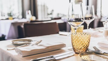 Ein elegant eingedeckter Tisch mit Besteck, Gläsern und einem weißen Tischdecke. Die Atmosphäre ist gemütlich und einladend. | © elizabeth.at