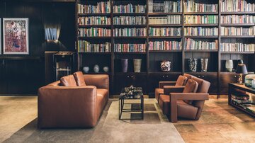 Ein elegantes Wohnzimmer mit gemütlichen Ledersofas und einer großen Bücherwand. Die Atmosphäre ist warm und einladend. | © elizabeth.at