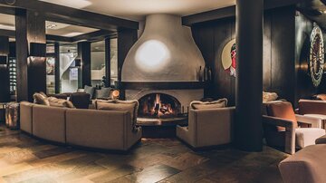 Gemütliche Lounge mit einem modernen Kamin und komfortablen Sitzgelegenheiten. Die warmen Farben und das elegante Design schaffen eine einladende Atmosphäre. | © elizabeth.at