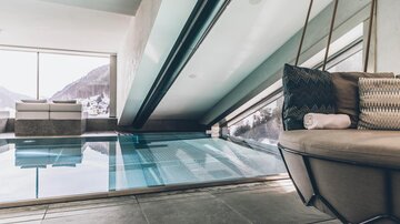 Ein moderner Innenraum mit einem Pool und großen Fenstern. Der Blick auf die Berglandschaft verleiht dem Raum eine entspannende Atmosphäre. | © elizabeth.at