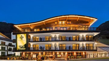Ein modernes Hotel mit einer stilvollen Fassade und einem gewölbten Dach. Die Beleuchtung hebt die Architektur bei Nacht hervor.