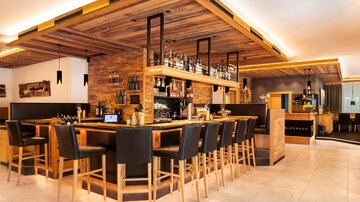 Eine stilvolle Bar mit Holzdekor und bequemen Stühlen. Die Beleuchtung sorgt für eine gemütliche Atmosphäre.