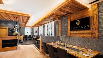 Ein modernes Restaurant mit Holzvertäfelung und eleganter Einrichtung. Die Tische sind gemütlich gedeckt und der Raum wirkt einladend.