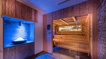 Ein stilvolles Wellnessbereich mit einer Holzsauna und sanften blauen Lichtern. Die entspannende Atmosphäre lädt zum Verweilen ein.