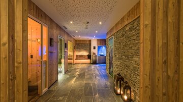 Ein eleganter Spa-Bereich mit Holzverkleidung und Steinwänden. Sanftes Licht schafft eine entspannende Atmosphäre.
