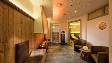 Ein gemütlicher Wellnessbereich mit warmem Licht und Holzverkleidung. Bequeme Sitze laden zur Entspannung ein.