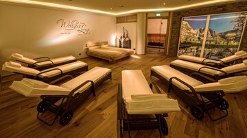 Ein entspannender Wellnessraum mit Liegen und warmem Holzfußboden. Sanfte Beleuchtung und dekorative Elemente schaffen eine ruhige Atmosphäre.