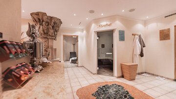 Ein stilvolles Spa mit hellem Interieur und einem eleganten Empfangsbereich. Der Raum ist mit warmer Beleuchtung und gemütlichen Elementen gestaltet.
