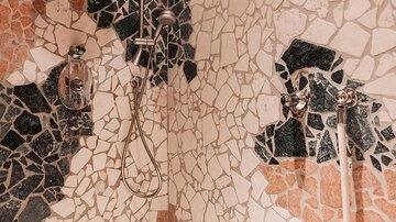 Eine moderne Dusche mit buntem Mosaikmuster aus verschiedenen Steinarten. Die Wände sind kreativ gestaltet und verleihen dem Raum eine ästhetische Note.