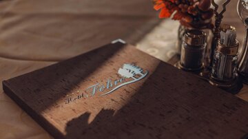 Ein stilvolles Menübuch aus Kork auf einem eleganten Tisch. Es sind auch dekorative Elemente wie Gewürzgefäße und Blumen zu sehen.