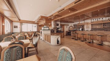 Ein gemütliches Restaurant mit Holzverkleidung und Barbereich. Die Sitzplätze sind hell und freundlich eingerichtet.