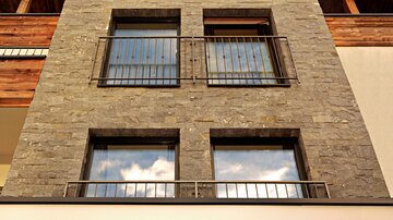 A modern building with a stone facade and large windows. At the top, the logo "PIMIA" is visible.