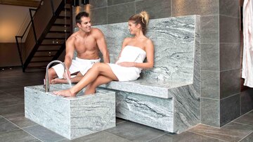 A modern spa with an elegant stone stool and a foot bath. A couple relaxes in a laid-back atmosphere.
