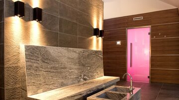 A modern bathroom with an elegant stone bench and a small sink. The walls are in neutral tones, and soft lighting creates a relaxed atmosphere.