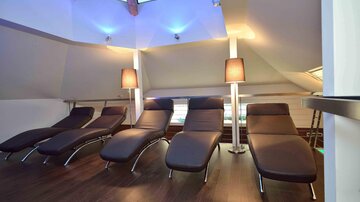 A stylish wellness area with cozy loungers and soft lighting. The large window front creates a bright and relaxing atmosphere.