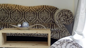 An elegant living room with a stylish sofa and a modern wooden table. The colors and patterns create a cozy atmosphere.