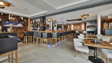 Ein modernes Restaurant mit einer stilvollen Bar und komfortablen Sitzbereichen. Die Atmosphäre ist gemütlich und einladend.