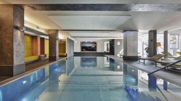 Ein eleganter Innenpool mit klaren Wasser und modernem Design. Der Raum ist mit bequemen Liegen und stilvollen Einrichtungen ausgestattet.