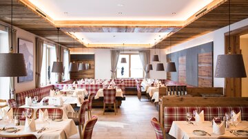 Ein elegantes Restaurant mit Holzdekor und stilvollen Sitzplätzen. Die Tische sind sorgfältig gedeckt und es strahlt eine gemütliche Atmosphäre aus.