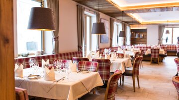Ein stilvolles Restaurant mit gedeckten Tischen und modernen Lampen. Die Einrichtung ist gemütlich und einladend.