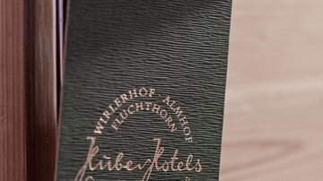 Ein Türschild aus grünem Material hängt an einer Tür. Es zeigt den Schriftzug „Hotel“ und einige Informationen über den Aufenthalt.