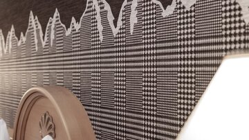Ein elegantes Schlafzimmer mit einem auffälligen Karomuster an der Wand. Die Decke ist mit stilvollen Kissen dekoriert.