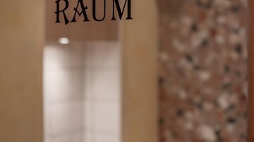 Ein Raum mit der Aufschrift "Frischluft Raum" und einem bequemen Holzregal. Im Hintergrund ist eine Wand mit einem schönen, strukturierten Design zu sehen.