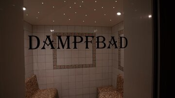 Ein Dampf-Bad mit gefliesten Wänden und Sitzbänken. Deckenleuchten sorgen für eine angenehme Atmosphäre.