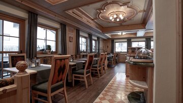 Ein einladendes Restaurant mit Holzdekor und gemütlichen Tischen. Die Fenster lassen viel Licht herein und sorgen für eine angenehme Atmosphäre.