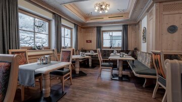 Ein gemütliches Restaurant mit Holzdekor und Tischen. Große Fenster bieten einen Blick auf die Natur draußen.