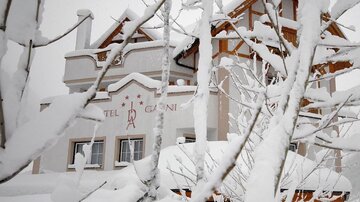 A hotel building is surrounded by snow and snow-covered branches. The winter landscape conveys a calm and charming atmosphere.