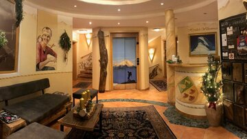 An inviting reception area with cozy furnishings and Christmas decorations. In the background, there is a beautiful view of the mountains.